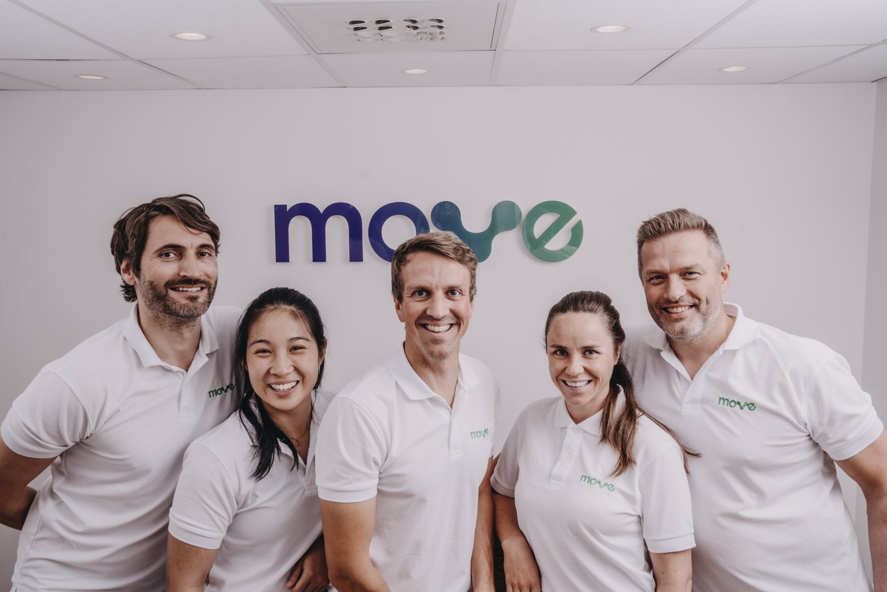 Behandlerne hos Move kiropraktikk foran Move-logoen i klinikken