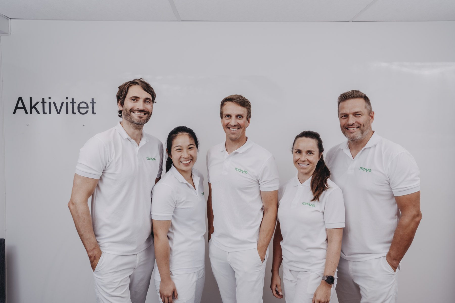Teamet hos Move kiropraktikk foran ordet «Aktivitet» på veggen i klinikken